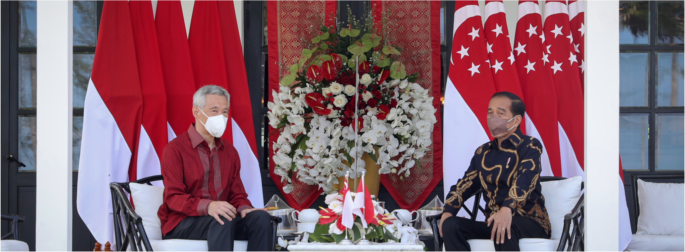 Lee Hsien Loong and Joko Widodo in masks, sitting near Indonesian and Singapore flags.
